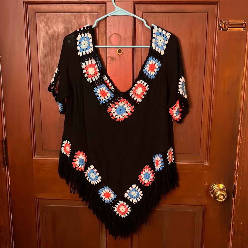 Shirt poncho style with crocheted squares and fringe. One size fits most.